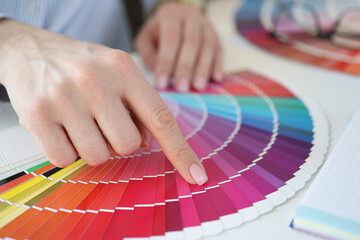Designer holding color swatch at desk in office closeup