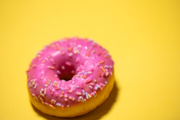 Homemade circle donut with pink icing and rainbow sprinkles