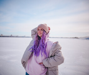 Fototapeta na wymiar a girl with purple hair stands on a snow-covered lake