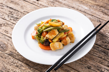 Stir fry chicken with vegetables on rustic wooden table