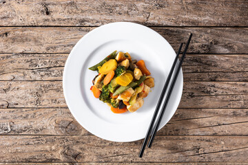 Stir fry chicken with vegetables on rustic wooden table. Top view