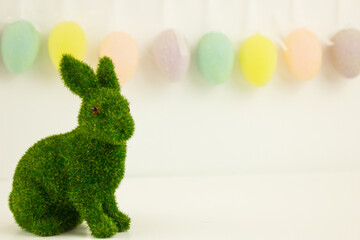 Green Easter bunny on a background of garlands of decorative eggs. Festive background. Happy Easter. Place for text.