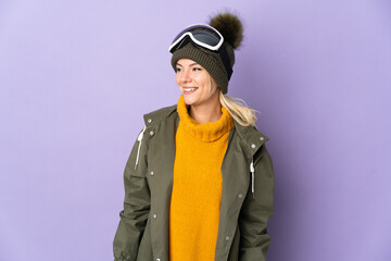 Skier Russian girl with snowboarding glasses isolated on purple background looking side