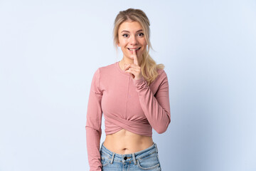 Blonde woman over isolated blue background showing a sign of silence gesture putting finger in mouth