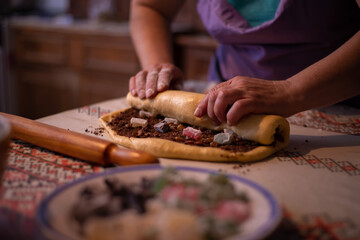 housewife rolling the dough filled with sweet ingredients to be placed in the oven tray. a traditional homemade cake recipe known as cozonac