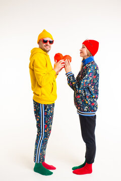 Stylish cute couple of man and woman in colorful clothes holding heart over white background