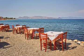Greek beach with traditional blue tables and chairs