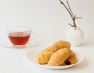  puff rolls with jam  on plate and glass cup of tea on white background