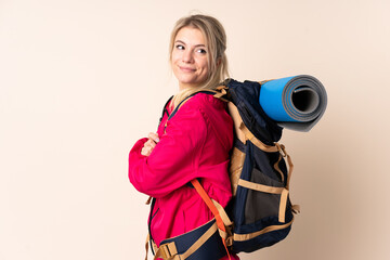 Mountaineer woman with a big backpack over isolated background laughing