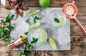 Lemonade, infused water or Mojito cocktail making. Mint, lime, ice ingredients and bar utensils. Top view.