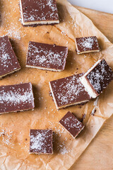 Organic raw vegan coconut bars with chocolate on kitchen table