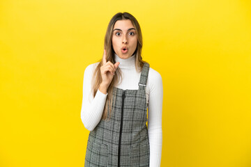 Young caucasian woman isolated on yellow background intending to realizes the solution while lifting a finger up