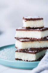 Organic raw vegan coconut bars with chocolate on kitchen table