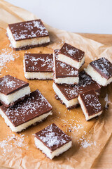 Organic raw vegan coconut bars with chocolate on kitchen table
