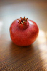 Ripe pomegranate on the brown wooden sunny table.