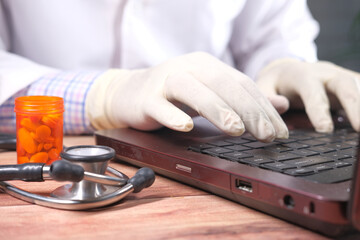 close up of doctor hand in latex gloves typing on laptop 