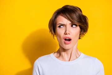 Photo of adorable shocked young woman wear white shirt looking empty space isolated yellow color background