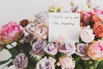 beautiful bright bouquet of colorful roses with white card with the inscription happy mother s day on spanish, concept of congratulations on the holiday