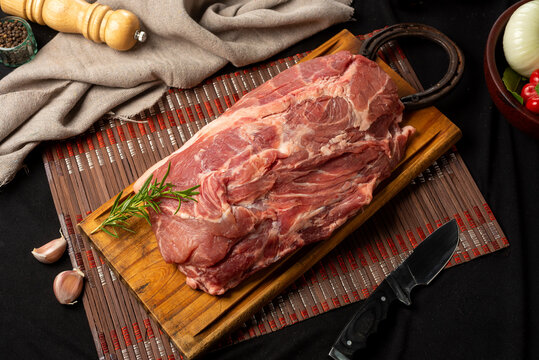 pork in a piece, cut bondiola on a table with vegetables rustic napkin pepper.