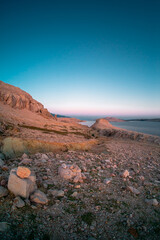Dry and rocky landscape at Dalmatian coast in Pag island, Croatia. Clear sky with color gradient in twilight time.