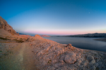 Morning panoramic view on rocky and arid landscape of Pag island on Adriatic coast in Croatia. Stones highlighted by colourful twilight light.