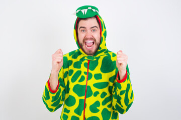 Fototapeta premium young caucasian man wearing a pajama standing against white background celebrating surprised and amazed for success with arms raised and open eyes. Winner concept.