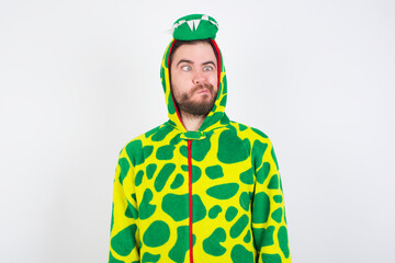 young caucasian man wearing a pajama standing against white background making grimace and crazy face, screaming out of control, funny lunatic expressing freedom and wild.