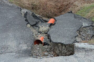 red plastic sewer pipe among pieces of broken asphalt on the road outside