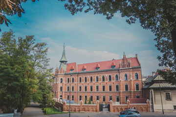 Obraz premium Higher Theological Seminary of the Archdiocese of Krakow. The Neo-Gothic building with orange brick wall and red roof with spire of Old Town in Krakow, Poland. The edifice was built between 1899-1902