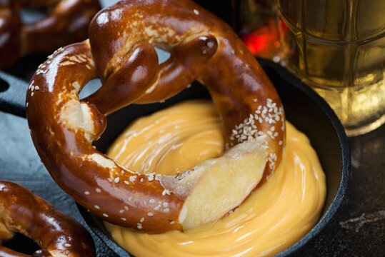 Close-up of cheese dipping sauce with german pretzel and beer, selective focus, horizontal shot