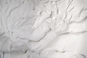 White rough surface with hard texture, putty, foam, background with bulky convex structure under hard light with contrasting shadows.