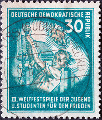 GERMANY, DDR - CIRCA 1951 : a postage stamp from Germany, GDR showing Flag-raising youth in front of the Brandenburg Gate. III. World Festival of Youth and Students for Peace