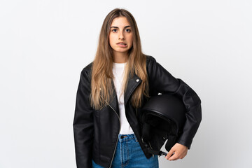 Young Woman holding a motorcycle helmet over isolated white background having doubts and with confuse face expression