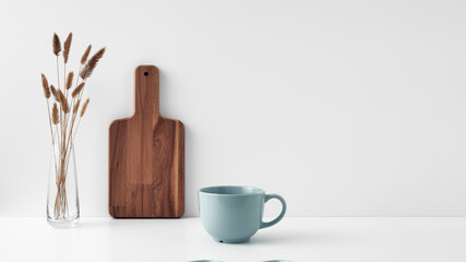 A mug, a potted houseplant, a clear vase and a wooden cutting board. Eco-friendly materials in the decor of the room, minimalism. Copy space, mock up
