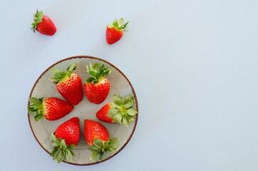 Festive grey background. Fresh ripe strawberries on a plate close up. Valentine's Day. Food backgrounds. Creative greeting card. Flat lay, top view.