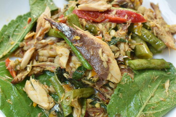 spicy stir fried mackerel fish with slice yard long bean and basil leaf on plate 