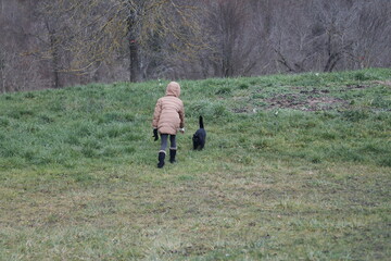 Un enfant en jaquette chaude brune s'approche d'un chat noir