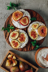 Healthy snack wholegrain rice crispbread crackers, figs and ricotta cheese on a wooden board.