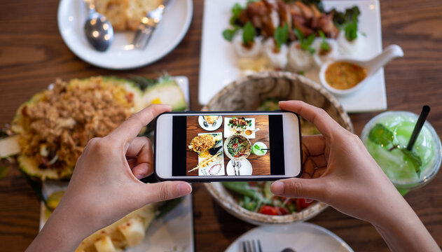 Women use mobile phones to take pictures of food or take live video on social networking applications. Food for dinner looks appetizing. Photography and take picture for review food concepts