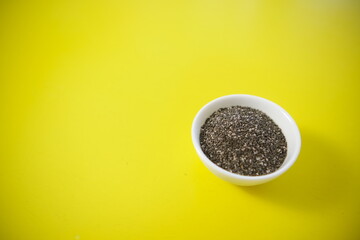 Quinoa is an organic food for a healthy diet. In a round bowl. Two white cups. Yellow background