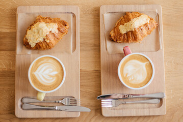 Tasty croissants with jot coffee on wooden background