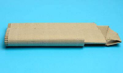 brown corrugated cardboard with torn edges on a light blue background