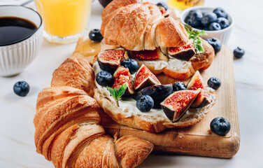 Delicious sweet sandwich with croissants, soft cheese, blueberries and figs
