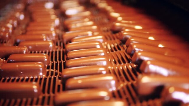 Small candy bars are getting glazed with liquid chocolate