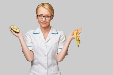 nutritionist doctor healthy lifestyle concept - holding organic avocado fruit and measure tape