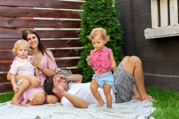 Happy family with two children on the green grass in the yard of their house.