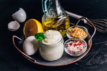 Homemade mayonnaise sauce with ingredient - olive oil, eggs, mustard and lemon on on a metal tray.