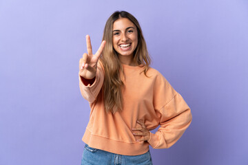 Fototapeta na wymiar Young hispanic woman over isolated purple background smiling and showing victory sign