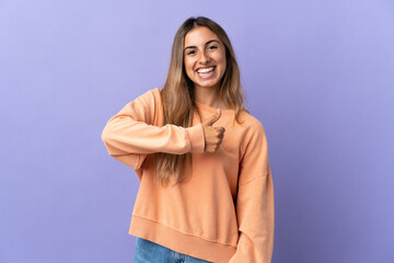 Young hispanic woman over isolated purple background giving a thumbs up gesture