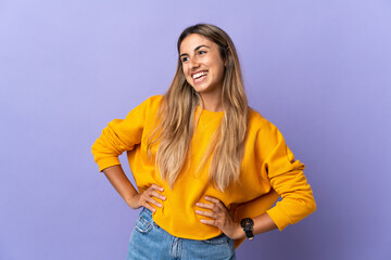 Young hispanic woman over isolated purple background posing with arms at hip and smiling